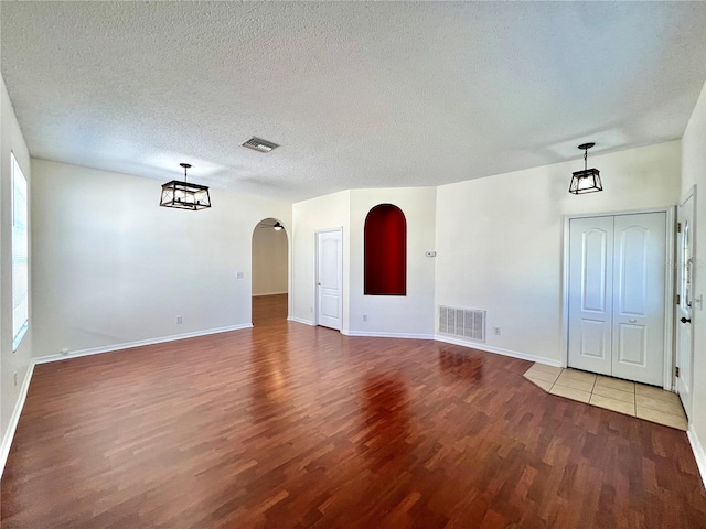 interior space with arched walkways, visible vents, a textured ceiling, and wood finished floors