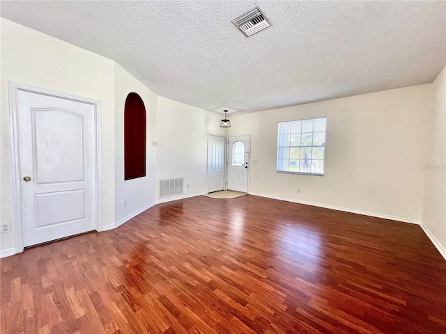 spare room featuring a textured ceiling, wood finished floors, visible vents, and baseboards