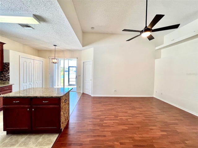 kitchen with light wood finished floors, a textured ceiling, open floor plan, and dark brown cabinets