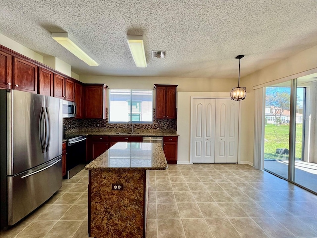 kitchen featuring stainless steel appliances, a sink, visible vents, dark brown cabinets, and tasteful backsplash