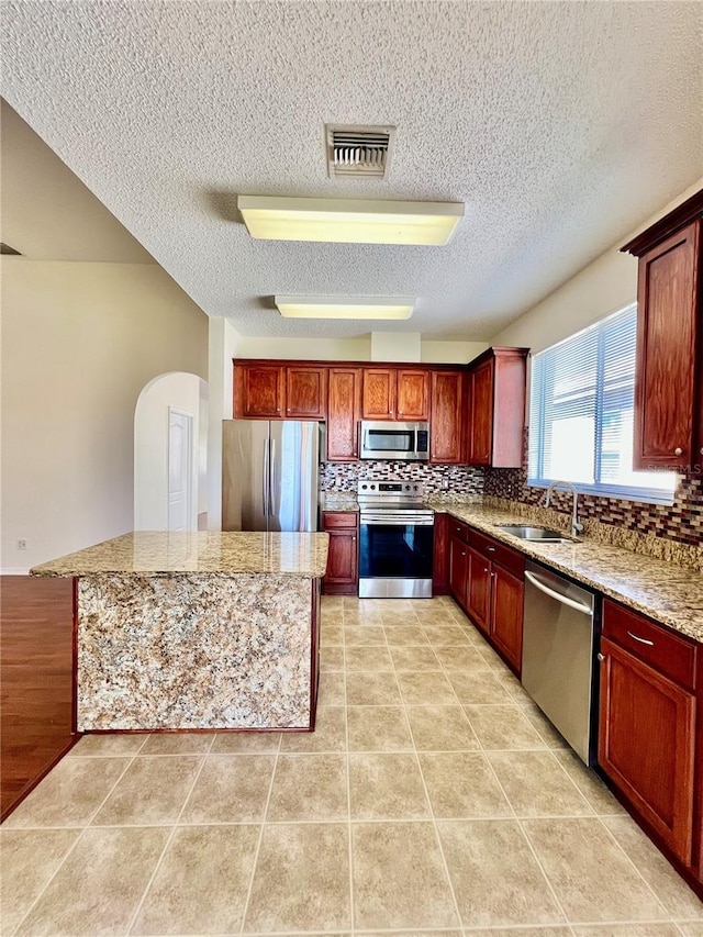 kitchen featuring light tile patterned floors, a sink, visible vents, appliances with stainless steel finishes, and decorative backsplash