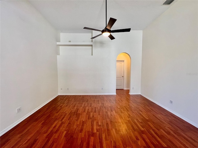 spare room with arched walkways, ceiling fan, wood finished floors, visible vents, and baseboards