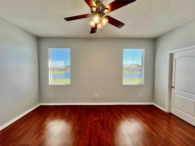 empty room featuring a textured ceiling, wood finished floors, and baseboards