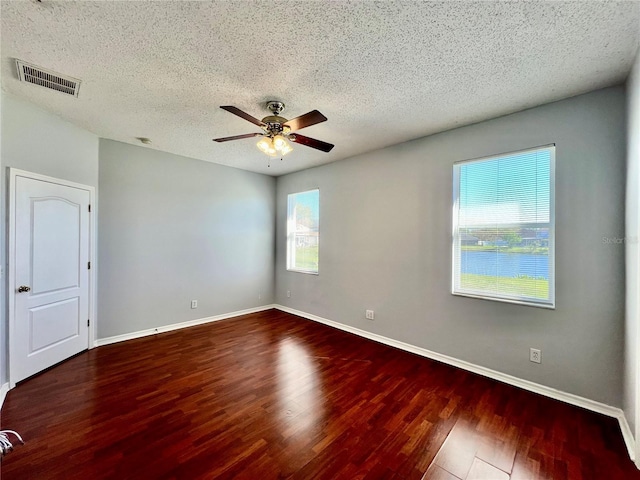 unfurnished room featuring baseboards, a textured ceiling, visible vents, and wood finished floors