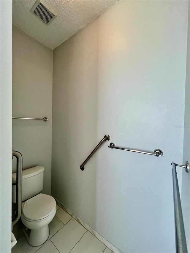 bathroom featuring toilet, a textured ceiling, visible vents, and tile patterned floors