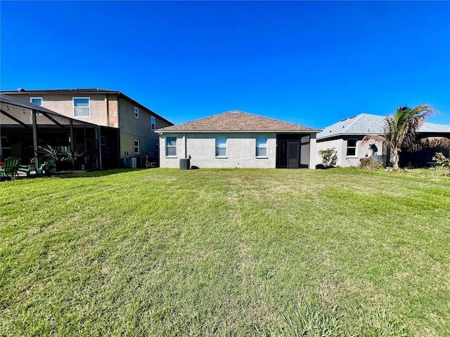 rear view of property with central air condition unit, a lawn, and stucco siding