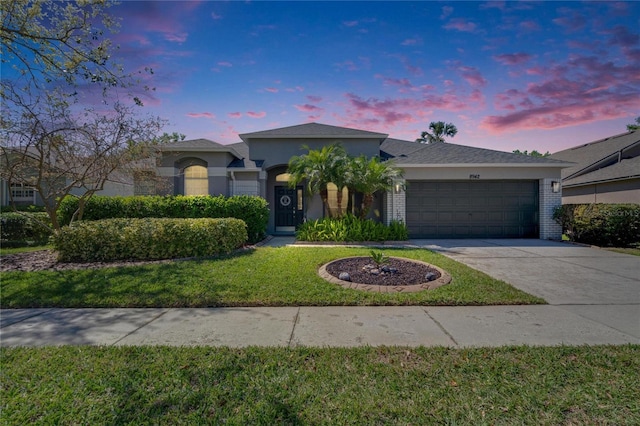 ranch-style home with concrete driveway, a garage, a front yard, and stucco siding