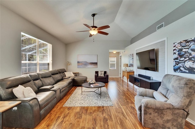 living room featuring light wood-type flooring, visible vents, lofted ceiling, and ceiling fan