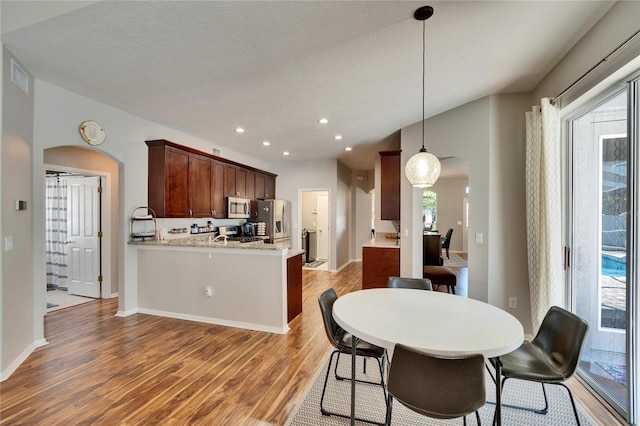 dining space featuring recessed lighting, plenty of natural light, light wood-style floors, and arched walkways