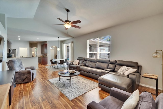 living area featuring light wood finished floors, baseboards, a ceiling fan, and vaulted ceiling