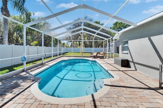 view of pool featuring glass enclosure, a patio, a fenced backyard, and a fenced in pool