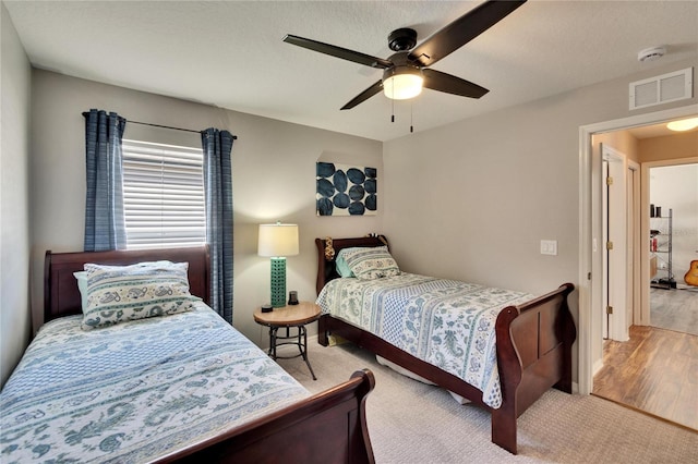 carpeted bedroom with visible vents, baseboards, and a ceiling fan