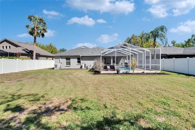 back of house with glass enclosure, a lawn, a fenced backyard, and stucco siding