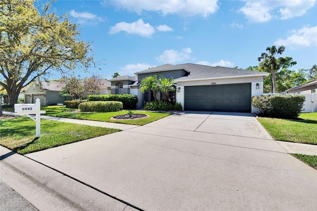 view of front facade featuring stucco siding, driveway, a front yard, an attached garage, and brick siding