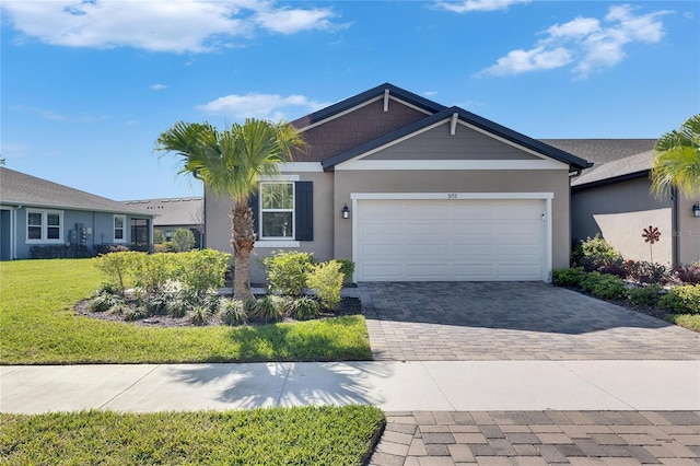 view of front of home featuring a front lawn, decorative driveway, an attached garage, and stucco siding