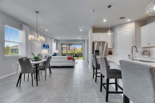 dining room featuring a chandelier, baseboards, visible vents, and a healthy amount of sunlight