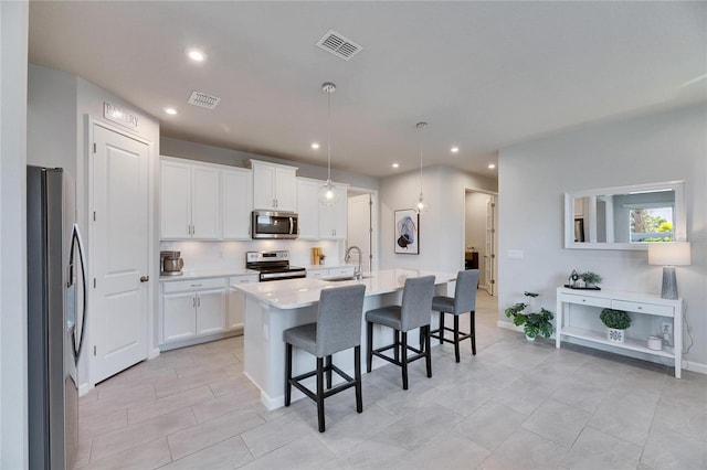 kitchen with a sink, visible vents, light countertops, appliances with stainless steel finishes, and a kitchen bar