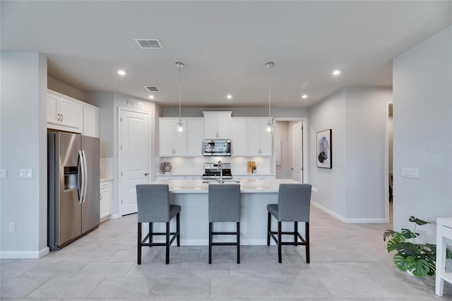 kitchen featuring a breakfast bar area, stainless steel appliances, light countertops, visible vents, and white cabinetry