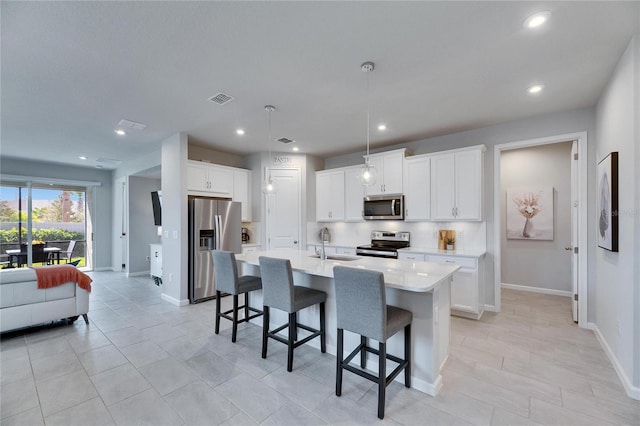 kitchen featuring a breakfast bar area, a sink, visible vents, appliances with stainless steel finishes, and backsplash