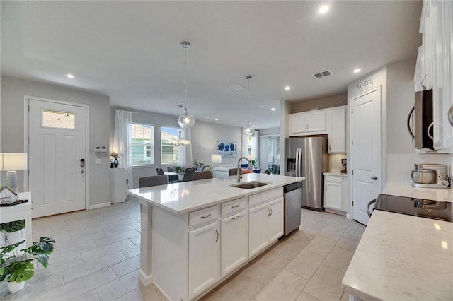 kitchen featuring recessed lighting, a sink, white cabinets, appliances with stainless steel finishes, and a center island with sink