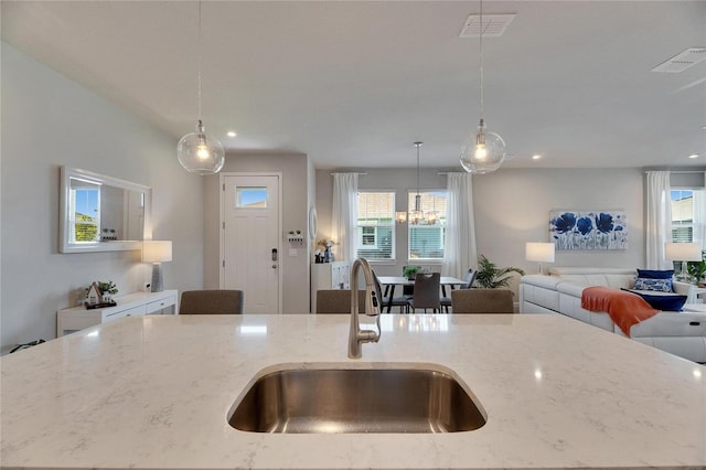 kitchen with open floor plan, a sink, visible vents, and light stone countertops