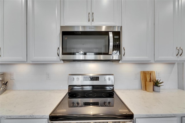 kitchen with white cabinetry, appliances with stainless steel finishes, tasteful backsplash, and light stone counters