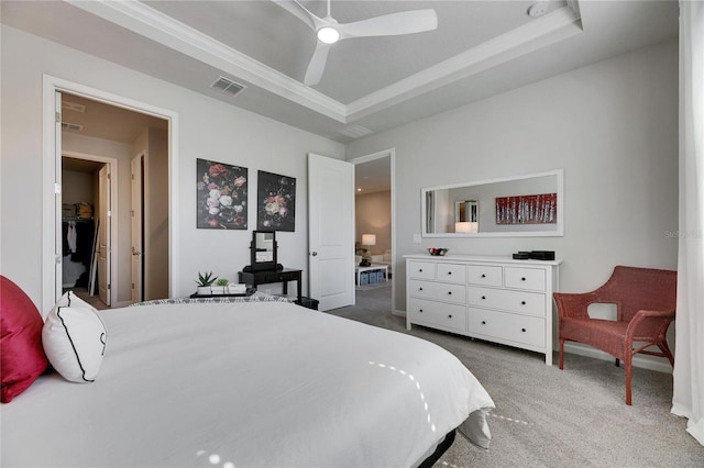 bedroom featuring a ceiling fan, a tray ceiling, carpet flooring, and visible vents