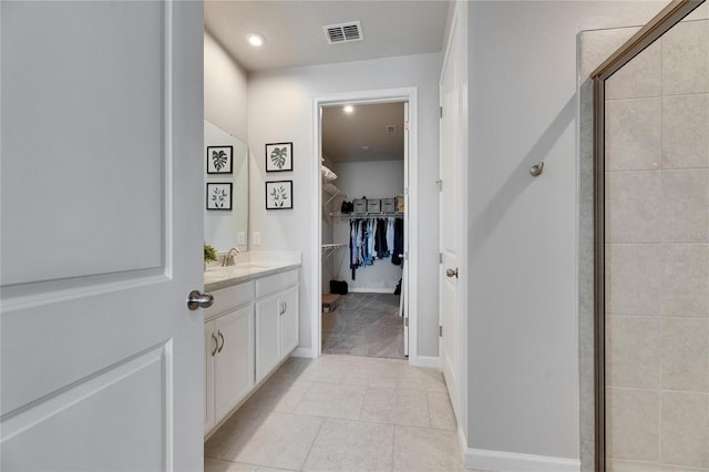 bathroom featuring a walk in closet, visible vents, a stall shower, vanity, and tile patterned floors