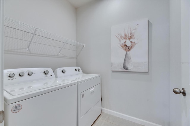 clothes washing area featuring laundry area, baseboards, washing machine and clothes dryer, and light tile patterned flooring