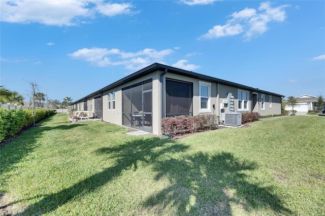 rear view of house featuring cooling unit, a sunroom, a lawn, and fence