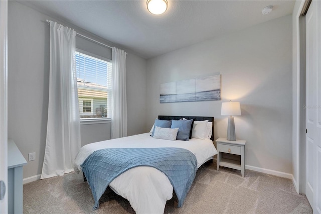 carpeted bedroom with a closet and baseboards