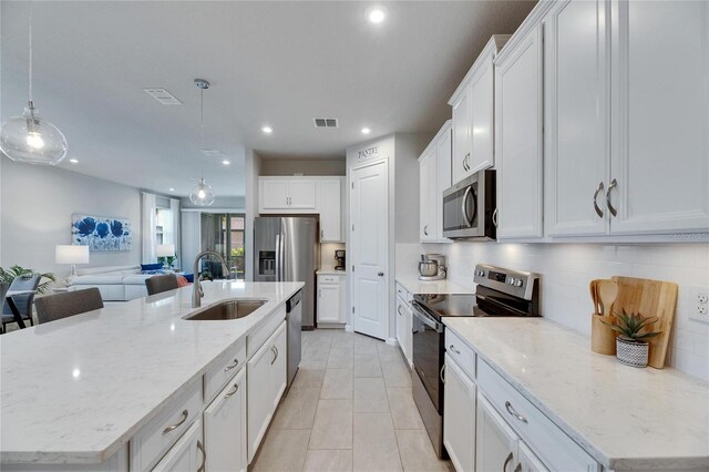 3753 Maxwell Park Dr, Sun City Center, FL 33573 - kitchen with appliances with stainless steel finishes, a sink, tasteful backsplash, white cabinets, and a large island