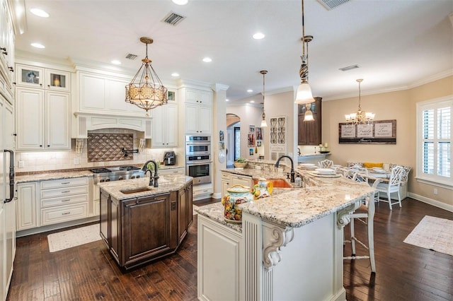 5914 Fitzgerald Rd, Odessa, FL 33556 - kitchen featuring a large island with sink, a chandelier, arched walkways, a sink, and dark wood-type flooring