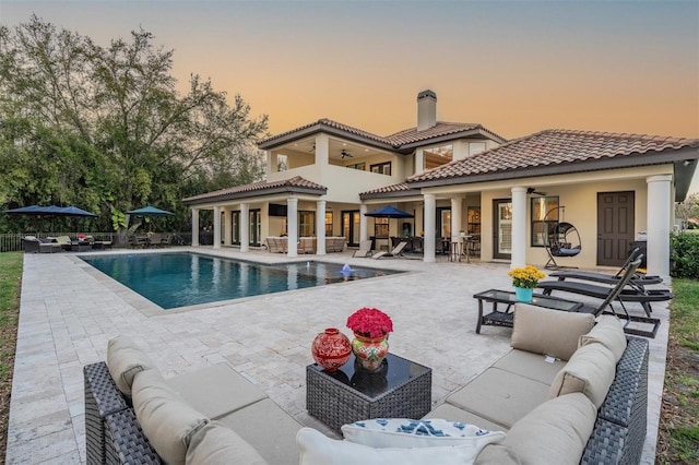 5914 Fitzgerald Rd, Odessa, FL 33556 - back of property at dusk featuring an outdoor hangout area, a ceiling fan, a patio area, and a chimney