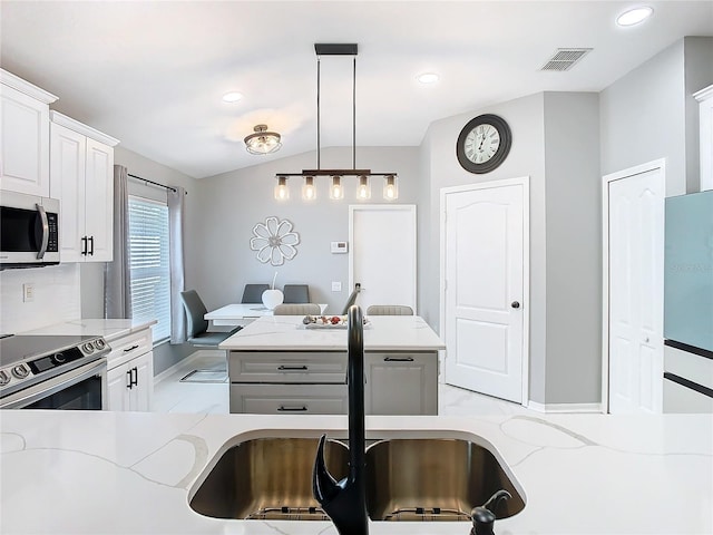 kitchen with visible vents, light stone countertops, stainless steel appliances, pendant lighting, and a sink