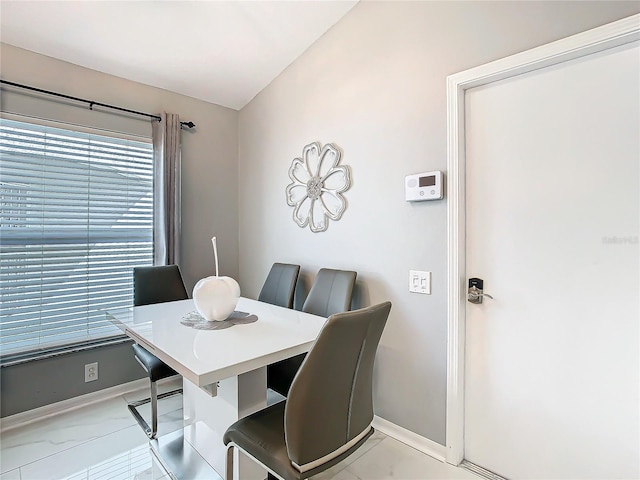 dining area featuring lofted ceiling, marble finish floor, and baseboards