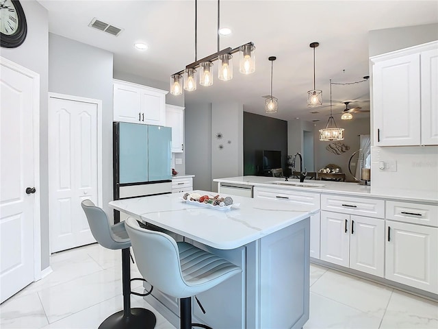 kitchen featuring refrigerator, visible vents, white cabinetry, a kitchen island, and a sink