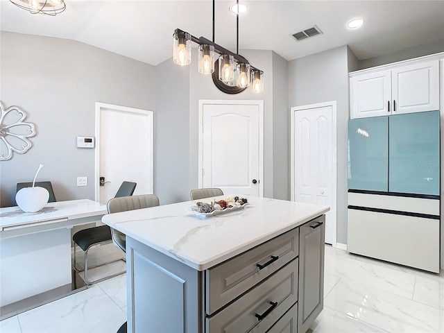 kitchen featuring lofted ceiling, visible vents, marble finish floor, freestanding refrigerator, and a center island