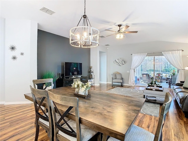 dining space with ceiling fan with notable chandelier, wood finished floors, visible vents, and baseboards