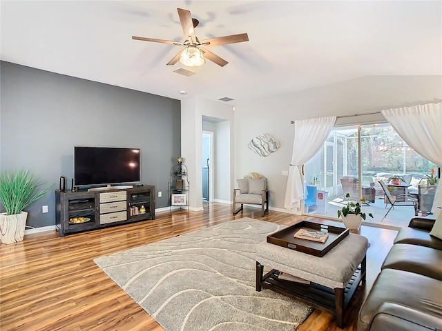 living area featuring a ceiling fan, baseboards, visible vents, and wood finished floors