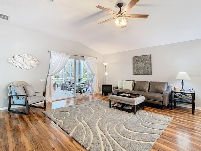 living area featuring lofted ceiling, visible vents, baseboards, and wood finished floors