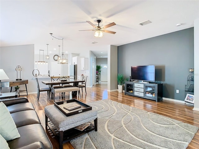 living area featuring light wood-style floors, visible vents, and baseboards