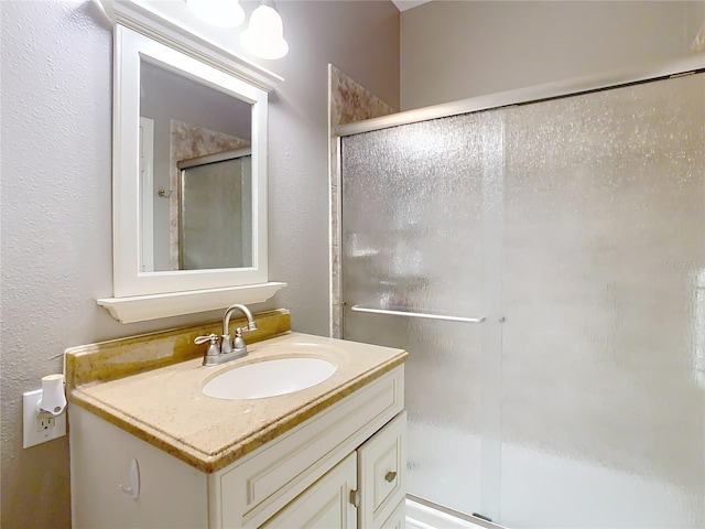 bathroom featuring a stall shower, a textured wall, and vanity