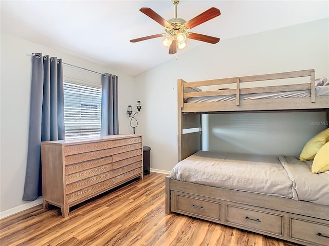 bedroom featuring lofted ceiling, baseboards, a ceiling fan, and light wood-style floors