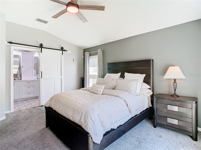 bedroom with lofted ceiling, ensuite bathroom, a barn door, light carpet, and visible vents