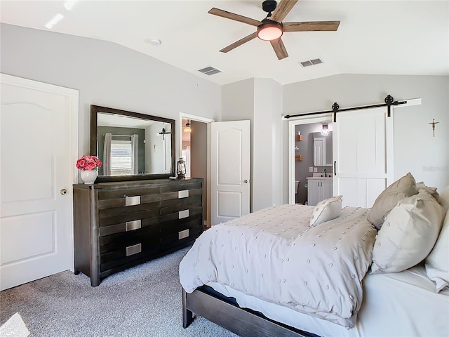 carpeted bedroom featuring lofted ceiling, a barn door, and visible vents