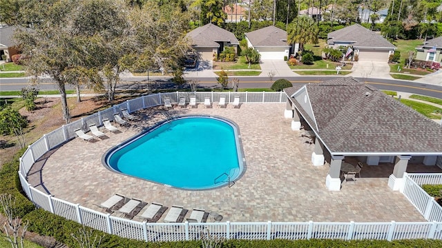 community pool with a patio area and a fenced backyard