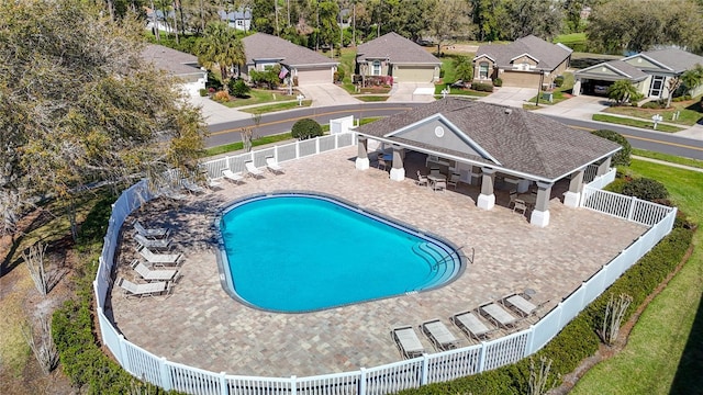 community pool featuring a fenced backyard, a residential view, and a patio