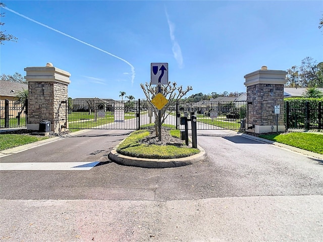 view of street with traffic signs, a gate, and a gated entry