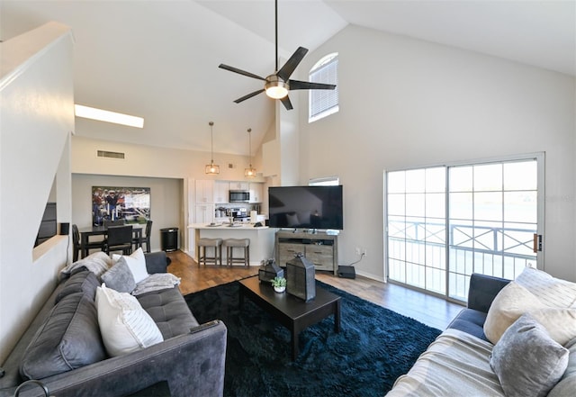 living room featuring high vaulted ceiling, ceiling fan, visible vents, and wood finished floors